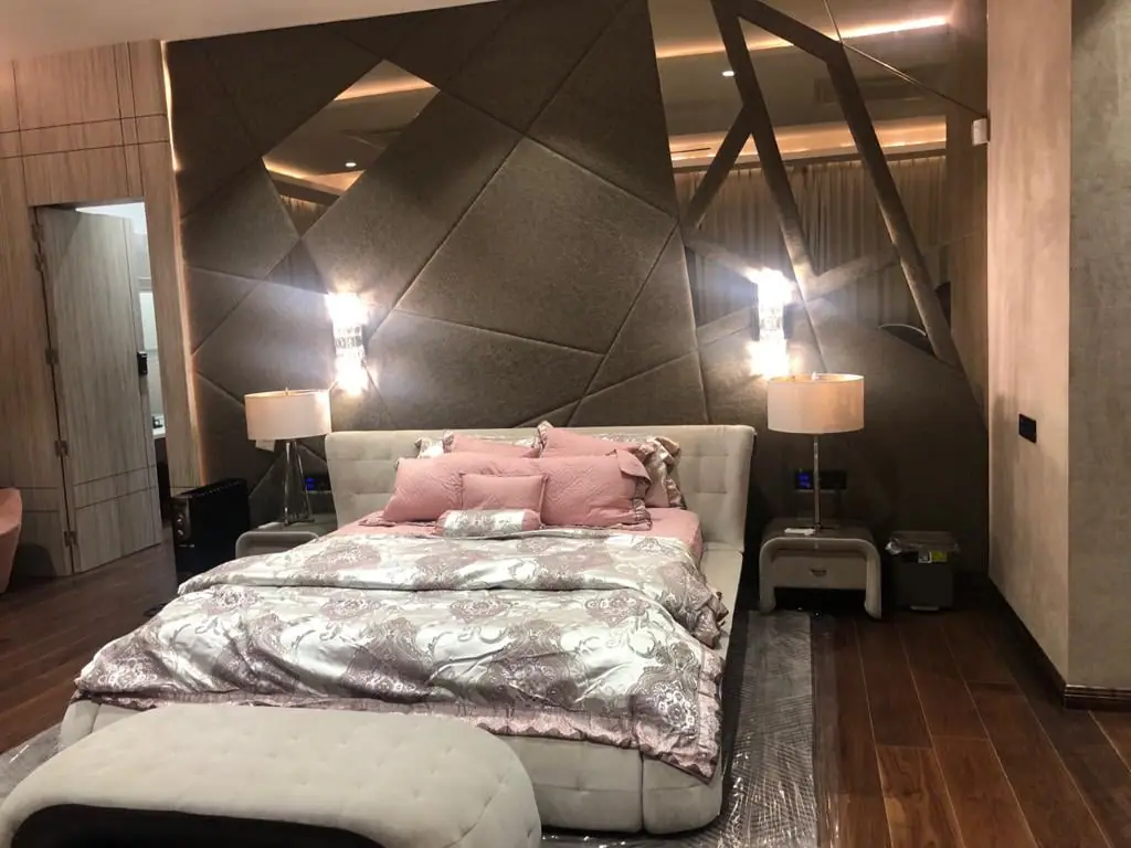 Master bedroom with a faceted upholstered headboard and wall lights