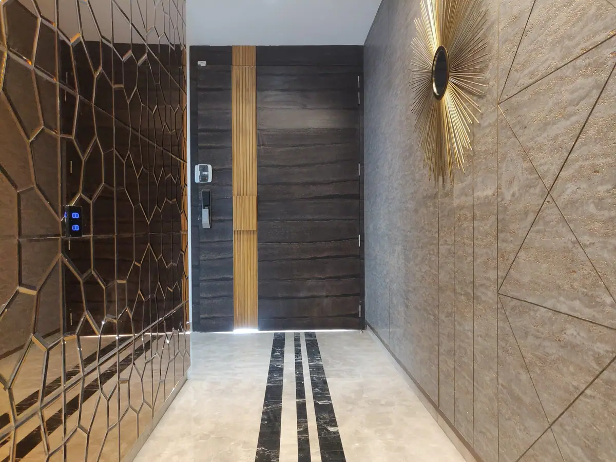 Entrance corridor with a brass-lined panel wall, timber door and stone floor inlay