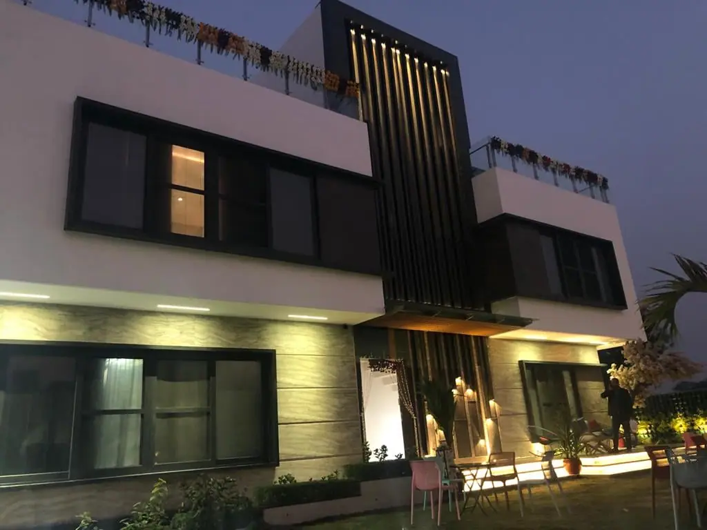 Arif House facade lit at dusk, with the timber-fin screen glowing