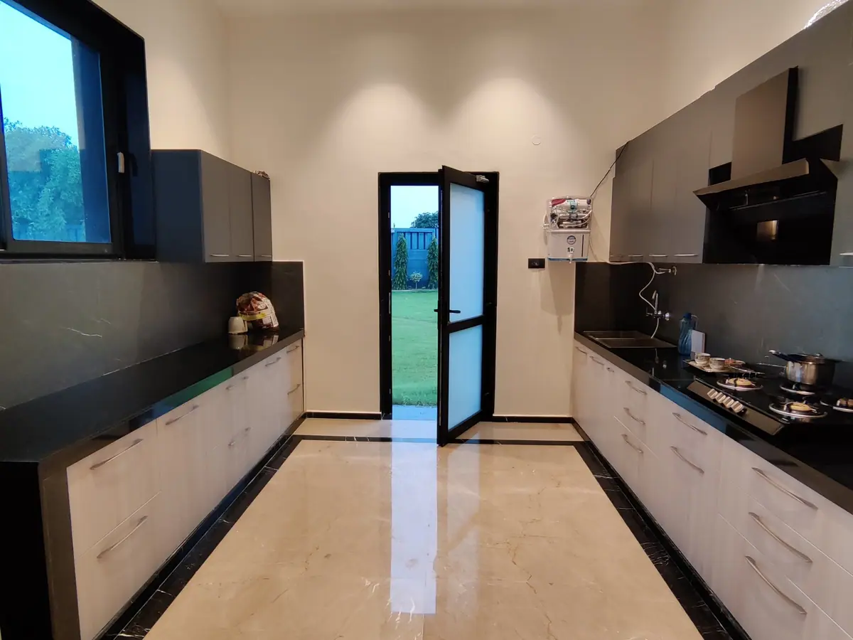 Galley kitchen with black stone worktops opening to the lawn