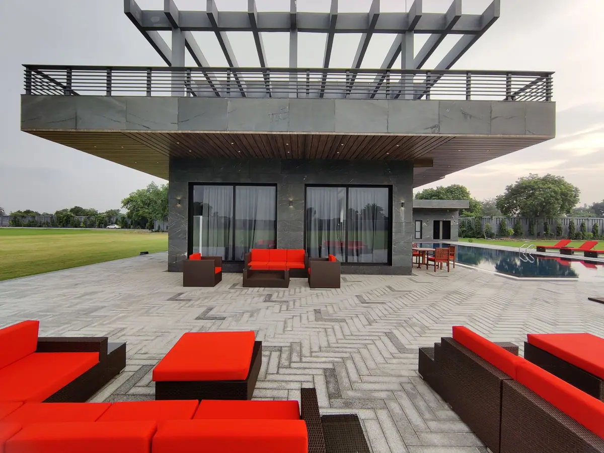 Red lounge seating on the herringbone terrace under the steel pergola
