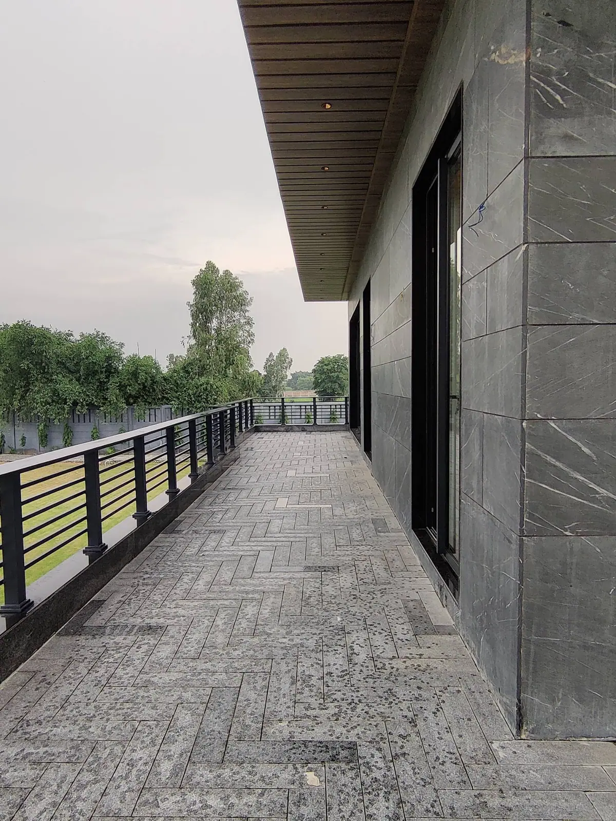 Upper-floor terrace with slatted rail and herringbone stone paving