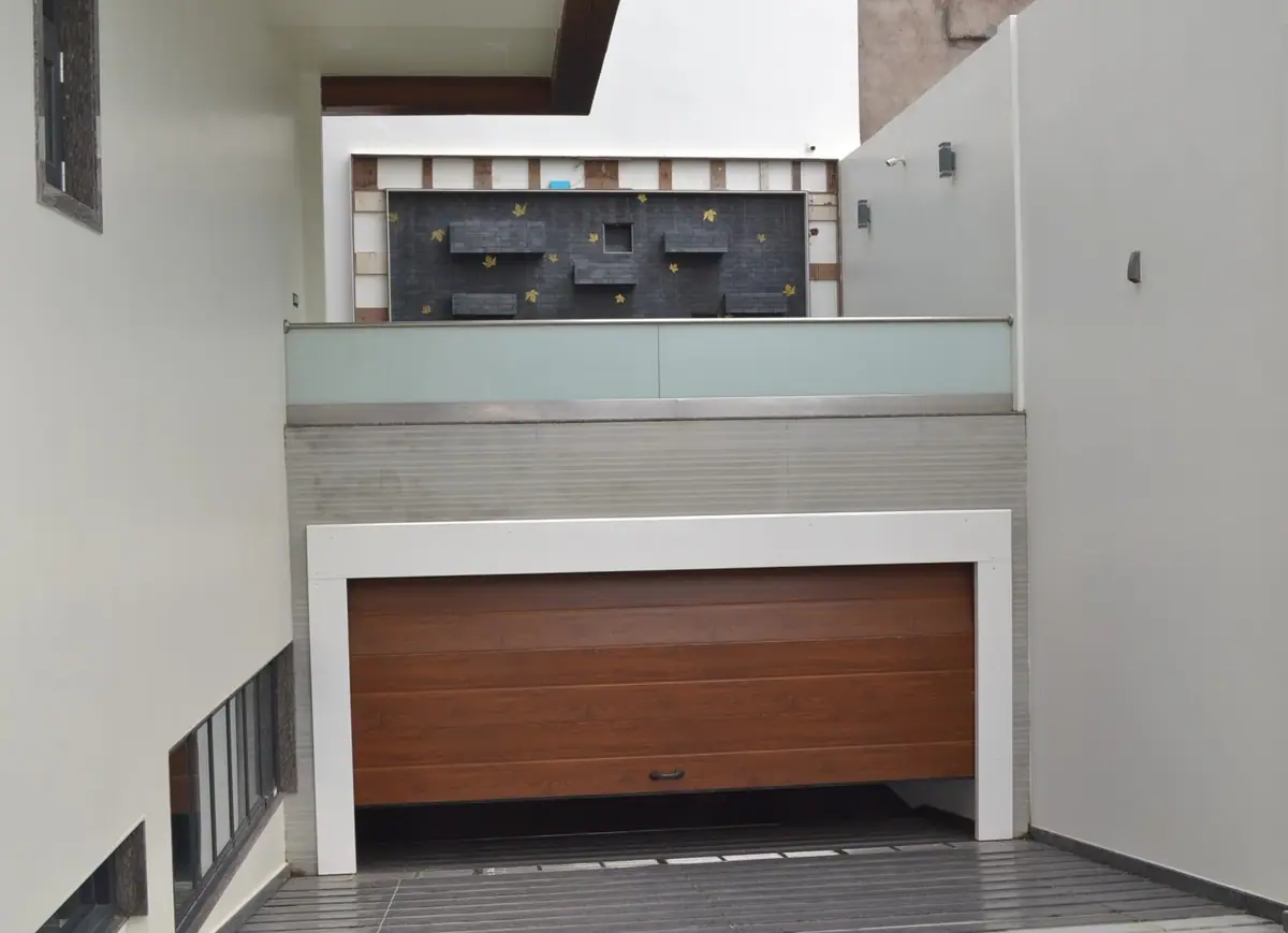 Ramp down to the basement garage door, with a dark stone feature wall above