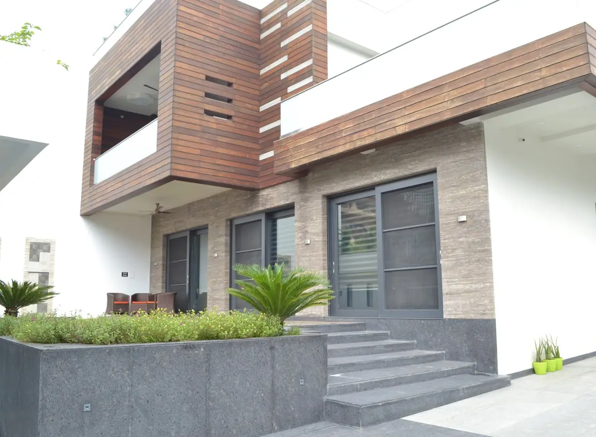 Garden front: cantilevered timber box over stone-clad walls, sliding doors and granite steps